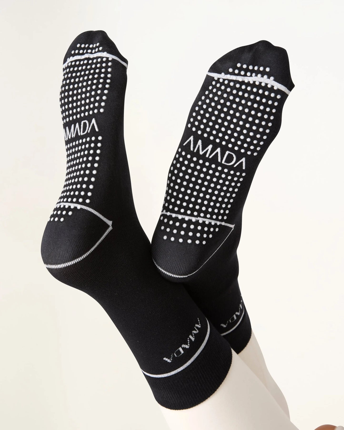 Black socks with white polka dots and 'AMADA' branding on a white background